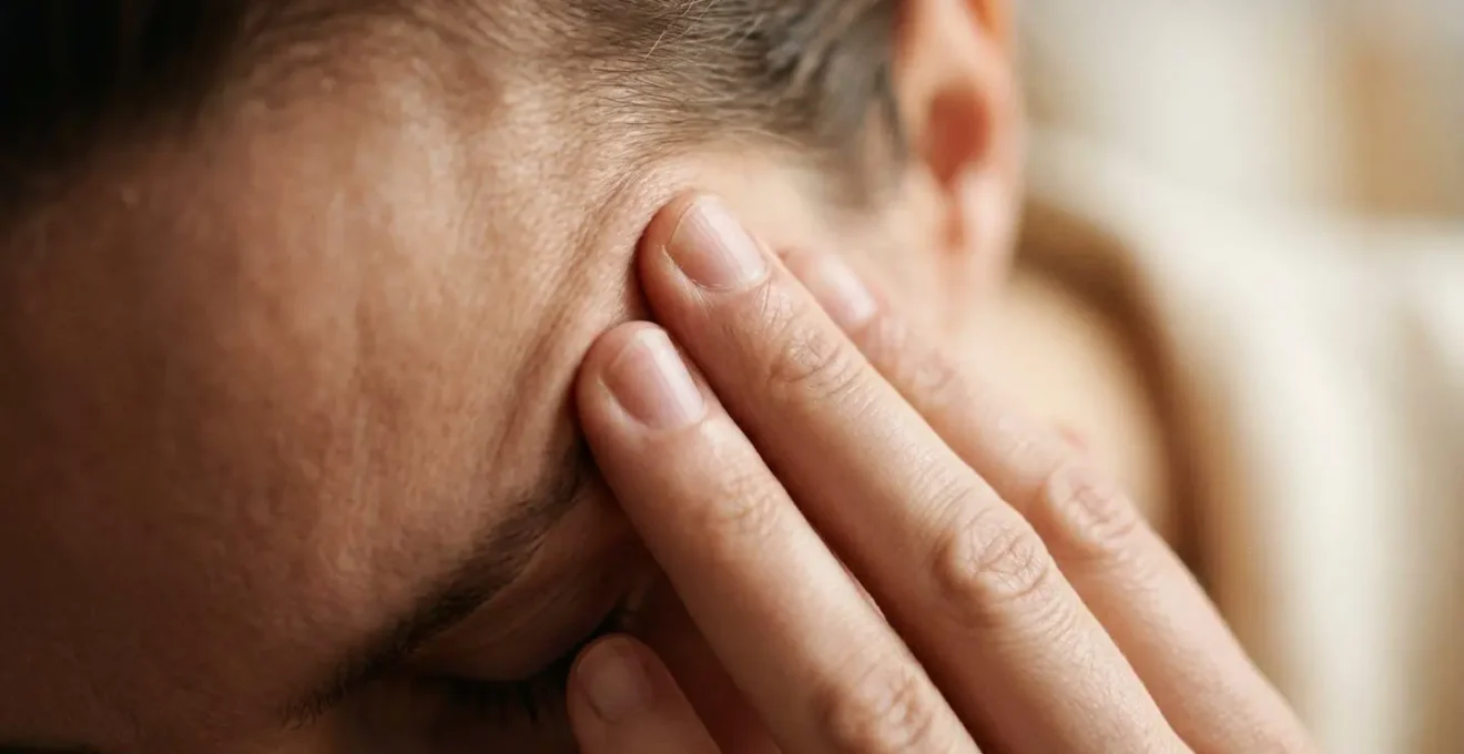 Gros plan sur des mains massant doucement les tempes, suggérant la fatigue cognitive